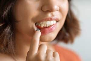 A woman points to red, irritated gums while highlighting an early sign of gum disease that often goes unnoticed.
